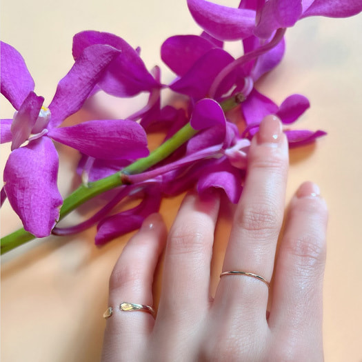 極細のリングを着用した手と花の写真